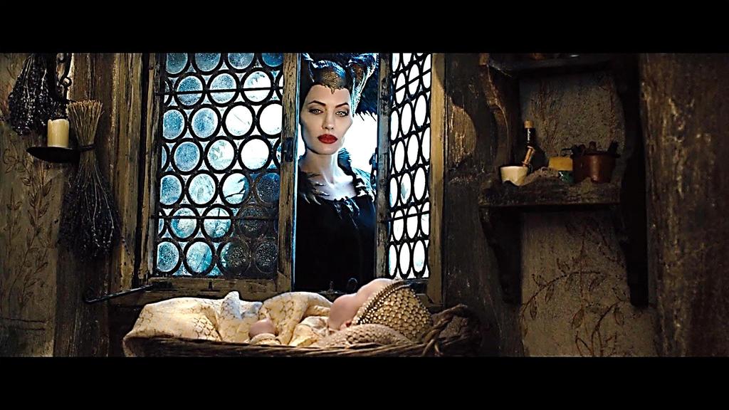 In the first scene that she looks at the child after the fairies have taken Aurora to the hidden cottage, the use of the half closed window to frame Maleficent as she looks at the baby, and the baby