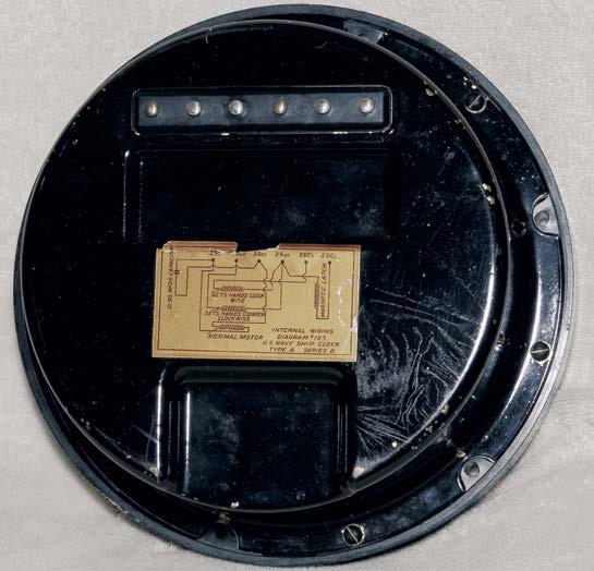 Figure 5, top. Entire clock is removed from the wallmounted case as a unit. Shown is the back cover plate with six electric spring contacts, which marry to the wallmounted case. Figure 6, center.