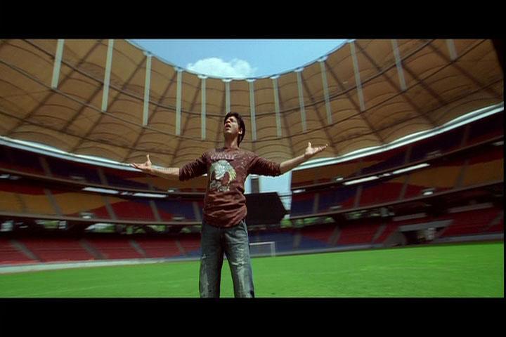A next cut introduces the extranarrative space showing Dev in the middle of the empty stadium stretching his arms in the air and singing about his feelings.
