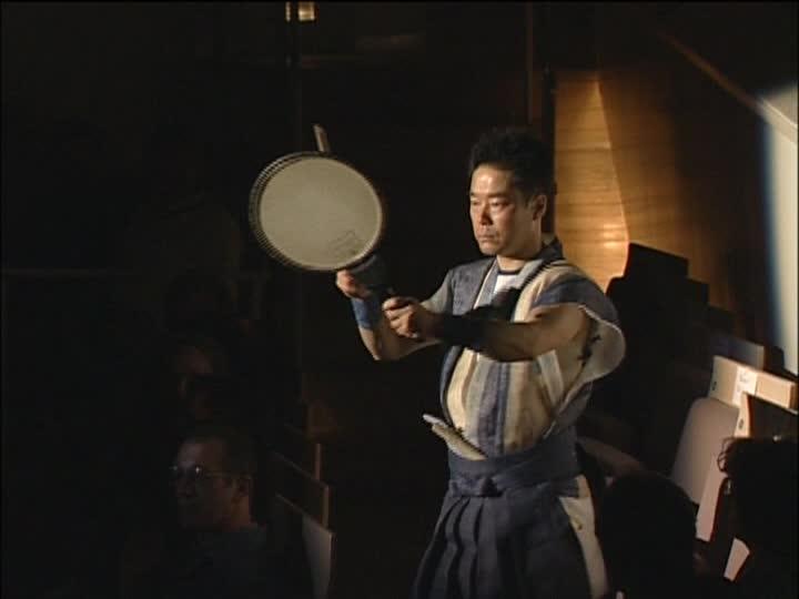 Figure 75. Hayashi Eitetsu holding an uchiwa-daiko Screenshot from a DVD of a 2000 performance in Berlin (Hayashi 2000) The rhythms in this opening section are sparse and repetitive.