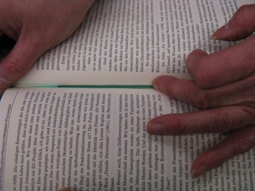 Insert the exposed adhesive side between 2 pages of the book, as close to the spine