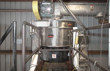 Overhead horizontal augers move sugar into the two VIBROSCREEN screeners in the