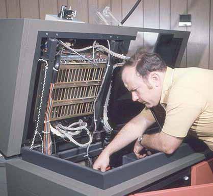 This 1980s photo shows Rich Hopkins with his head inside the Mergenthaler VIP phototypesetting system. It had a spinning disk carrying up to six fonts, which stopped after each letter was exposed.