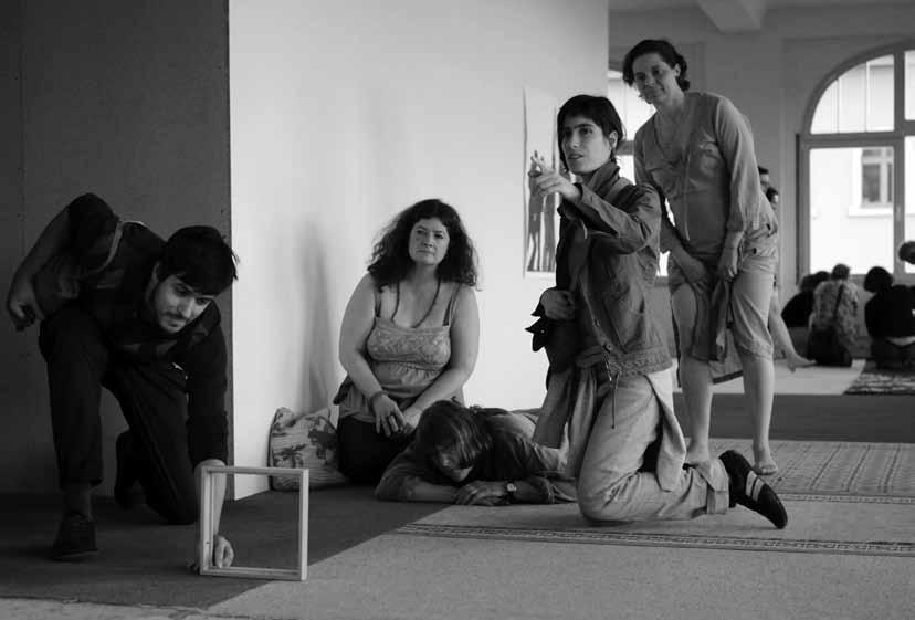 SLIKA 5: Preverjanje okvirja, 6. berlinski bienale, 2010 (Foto: Marko Krojač) Na ležeči fotografiji je 5 oseb, 4 ženske in en moški v razstavnem prostoru galerije. Obrnjeni so proti nam.
