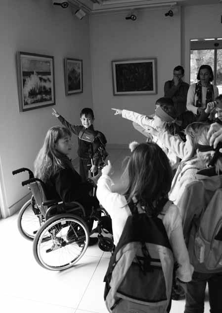 Pod to sliko na invalidskem vozičku sedi Katrin Modic, s telesom je obrnjena proti desni strani fotografije.