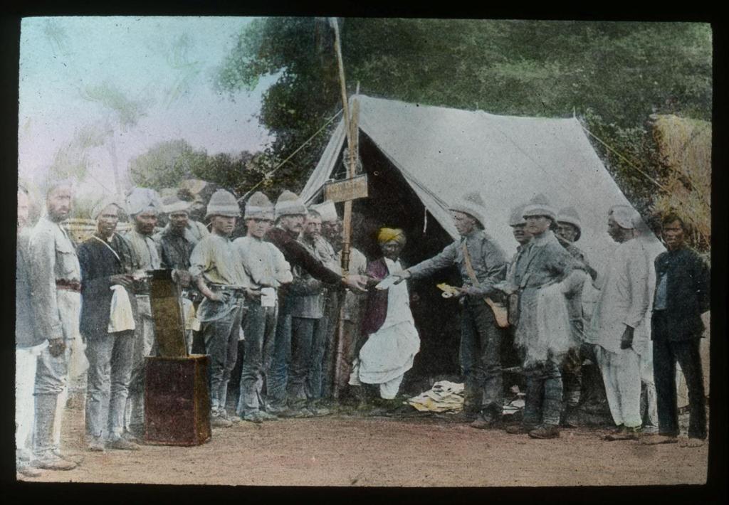 The Postal Museum, 2011-0502-16 In this hand-coloured lantern slide a tent acts as a Post Office at a military camp in India. The First World War was a truly global conflict.