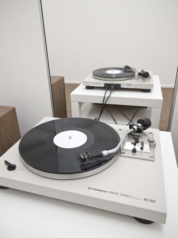 One follows a short corridor cushioned throughout with a common, office-style grey carpet, and we are suddenly in a room with a view: A hi-fi with a pair of speakers, and a spinning turntable;