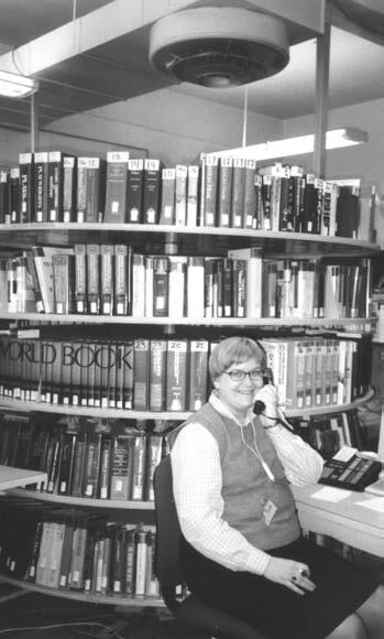 Figure 1. Sadra Byres is pictured with the two-tier telephoe referece rotary wheel at the Milwaukee (Wisc.) Public Library. The wheel is operated electrically with idepedetly revolvig shelves.