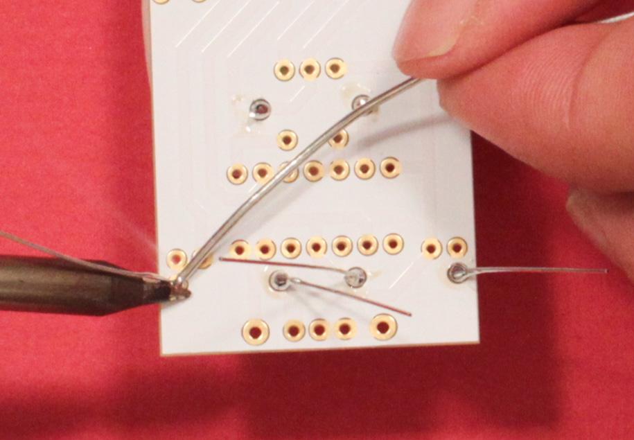 TOP TIP: Bring the soldering iron to your first pin. Place the edge of the tip against both the pin and the gold metallic pad.
