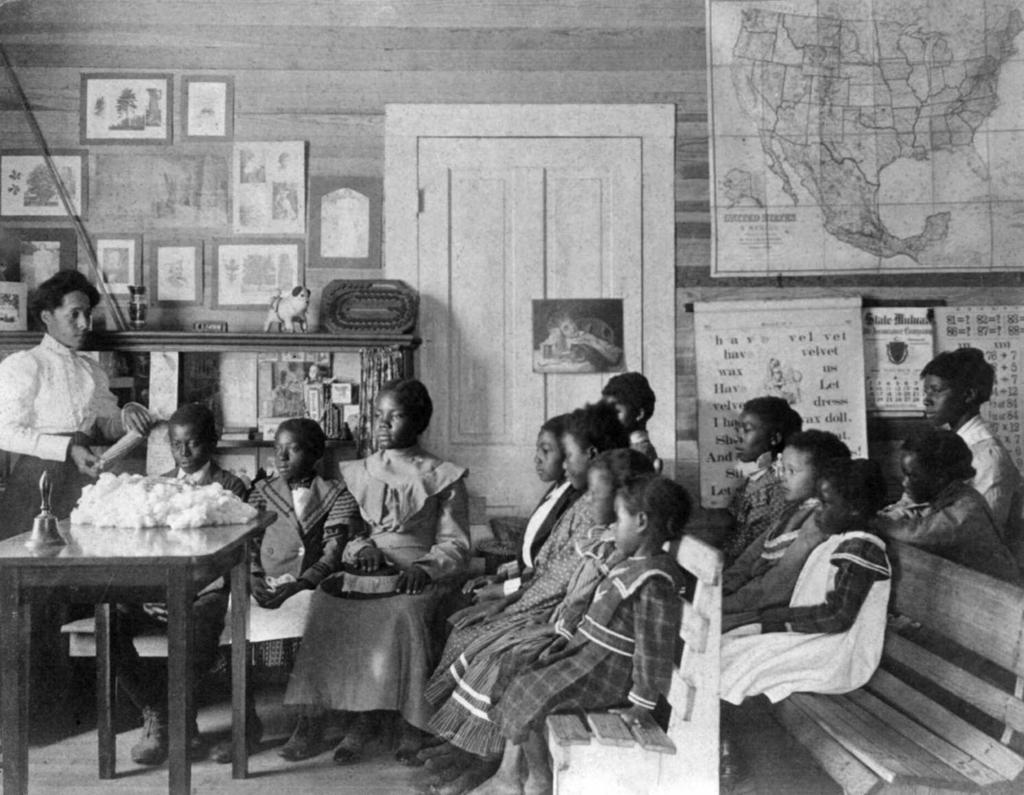 African American children and teacher in classroom studying